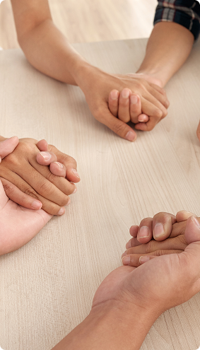 four-unrecognizable-people-sitting-around-table-holding-each-other-s-hands-middle